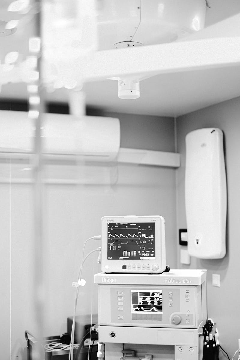 Black and white photo of an ECG monitor in a hospital showing vital signs and medical equipment.